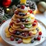 pancakes en forme de sapin de Noël décorés de fruits rouges et bananes sur assiette festive