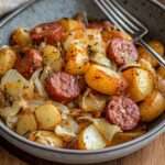 Poêlée de kielbasa dorée avec pommes de terre et chou sautés, servie dans une cocotte rustique.