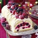 Bûche de Noël roulée garnie de mascarpone et fruits frais, décorée de sucre glace et menthe.