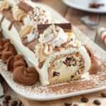 Bûche de Noël au café décorée de cacao, grains de café et sucre glace, roulée et garnie de crème au café.