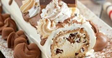 Bûche de Noël au café décorée de cacao, grains de café et sucre glace, roulée et garnie de crème au café.