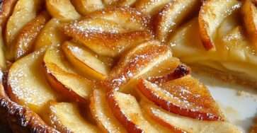 Tarte alsacienne aux pommes avec flan crémeux, pommes en rosace et nappage abricot brillant.