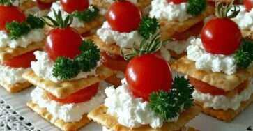 Mini millefeuilles salés composés de crackers croustillants, fromage frais et tomates cerises en décoration.