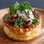 Vol-au-vent feuilleté garni de champignons forestiers crémeux aux herbes fraîches, servi chaud pour une entrée festive et élégante.