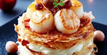 Millefeuille de Saint-Jacques dressé avec crème de panais, noisettes concassées et chips de chorizo croustillantes.