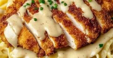 Assiette de fettuccines Alfredo crémeuses garnies de tranches de poulet croustillant doré.