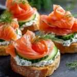Crostinis au saumon croustillants garnis de fromage frais aux herbes, concombre finement tranché et saumon fumé, décorés d’aneth frais