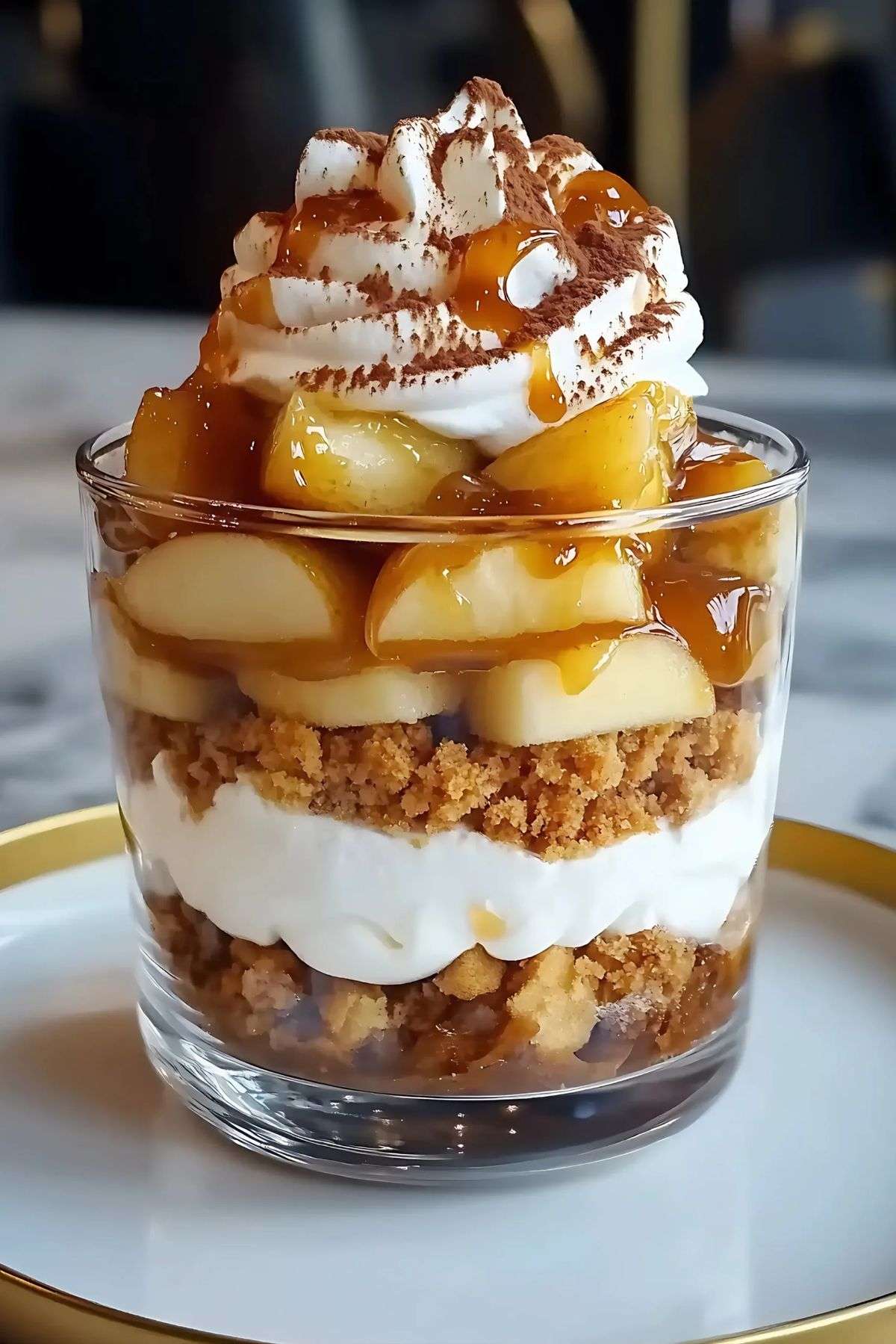 Verrines aux pommes caramélisées, base biscuitée façon crumble, crème fouettée et filet de caramel au beurre salé, décorées de cacao