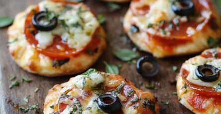 Mini-pizzas apéritives dorées au four, garnies de sauce tomate, mozzarella fondue et tranches de pepperoni avec un peu d’herbes