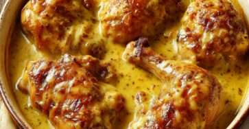 Cuisses de poulet mijotées dans une sauce crémeuse à la moutarde à l’ancienne, servies en cocotte.