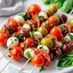 Brochettes d’antipasti italiennes composées de tomates cerises, mozzarella, salami, olives et basilic, disposées sur un plateau pour l’apéritif