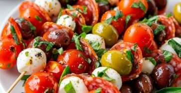 Brochettes d’antipasti italiennes composées de tomates cerises, mozzarella, salami, olives et basilic, disposées sur un plateau pour l’apéritif