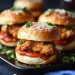 Mini-sandwichs garnis de poulet croustillant au parmesan avec salade verte et sauce, présentés sur un plateau pour un apéritif ou buffet