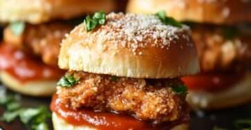 Mini-sandwichs garnis de poulet croustillant au parmesan avec salade verte et sauce, présentés sur un plateau pour un apéritif ou buffet