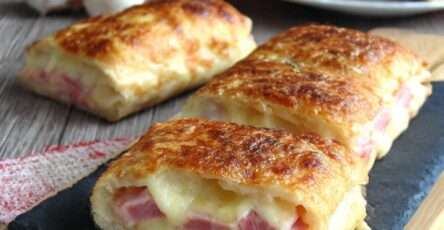 Croque-monsieur roulé doré à la poêle, coupé en bouchées apéritives avec fromage fondu et jambon.