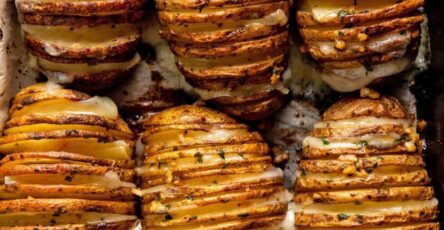 Pommes de terre Hasselback croustillantes au four, dorées, garnies d’ail, d’herbes et de beurre fondu.