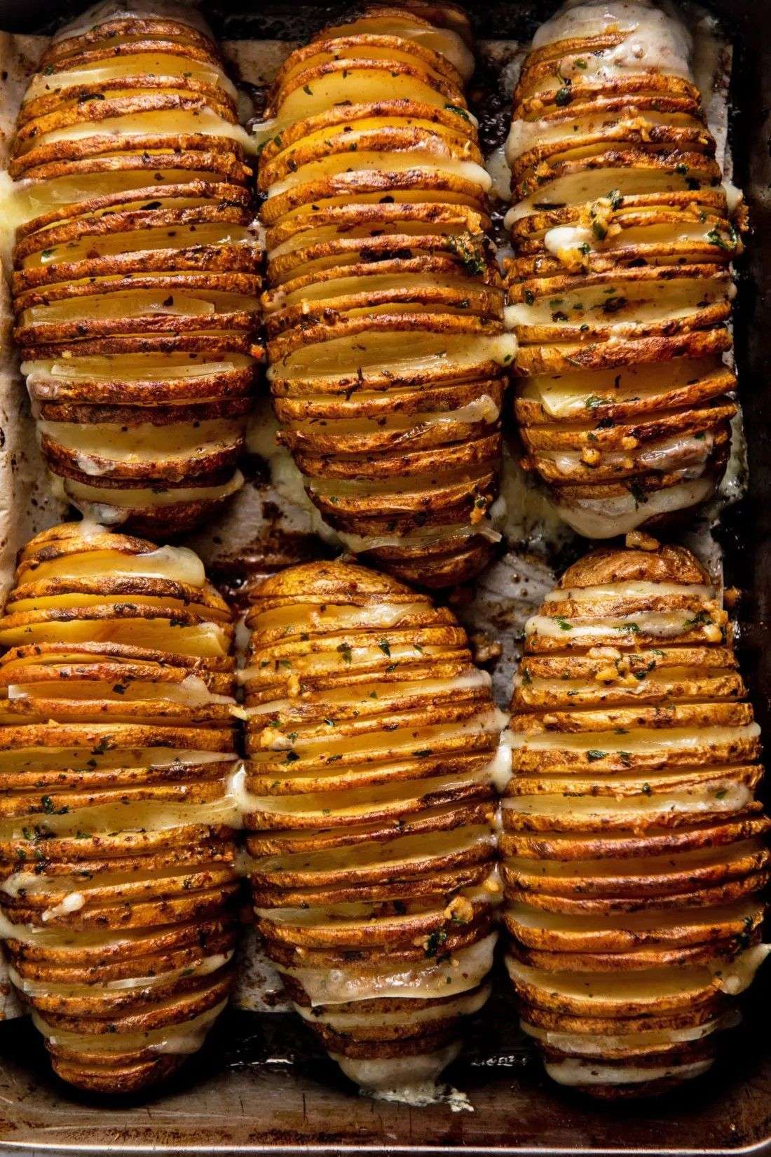 Pommes de terre Hasselback croustillantes au four, dorées, garnies d’ail, d’herbes et de beurre fondu.