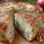 Cake salé aux pommes, camembert et noix doré au four, tranché sur une planche, texture moelleuse et morceaux de fromage fondant visibles.