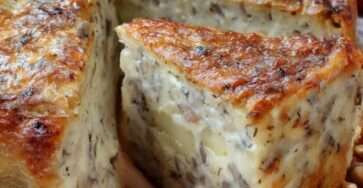 Cake salé aux pommes, camembert et noix doré au four, tranché sur une planche, texture moelleuse et morceaux de fromage fondant visibles.