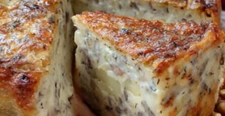 Cake salé aux pommes, camembert et noix doré au four, tranché sur une planche, texture moelleuse et morceaux de fromage fondant visibles.