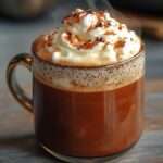 Chocolat chaud maison onctueux au chocolat noir, surmonté de crème fouettée, copeaux de chocolat et cacao saupoudré.