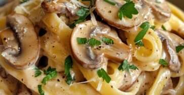 Pâtes crémeuses aux champignons de Paris et parmesan râpé, sauce onctueuse brillante, persil frais ciselé et poivre noir sur le dessus