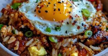 Bol de riz frit au bacon croustillant avec légumes, œuf au plat au jaune coulant et graines de sésame, servi bien chaud