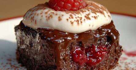 Brownie fondant au chocolat noir avec cœur coulant caramel et framboises fraîches, servi avec chantilly maison et cacao saupoudré