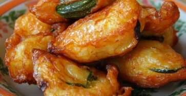 Beignets de courgettes croustillants et dorés sortis de friture, enrobés d’une pâte légère, servis chauds sur papier absorbant