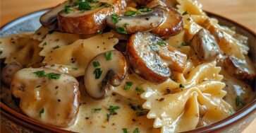 Farfalles crémeuses aux champignons poêlés, nappées de sauce onctueuse à la crème, garnies de persil frais et de parmesan