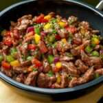 Bœuf sauté aux poivrons rouges, verts et jaunes, nappé de sauce soja brillante et servi chaud avec des herbes fraîches.