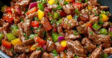 Bœuf sauté aux poivrons rouges, verts et jaunes, nappé de sauce soja brillante et servi chaud avec des herbes fraîches.