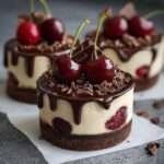 Mini cheesecake au chocolat noir avec cerises intégrées, base biscuit cacao et nappage brillant, décoré de copeaux de chocolat.