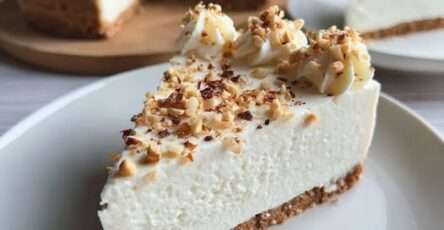 Cheesecake crémeux sans cuisson aux noisettes concassées, base biscuitée dorée et surface lisse parsemée d’éclats croquants.