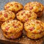 Muffins salés au jambon et fromage dorés au four, texture moelleuse avec emmental fondant et parmesan gratiné sur le dessus.