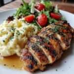 Assiette de poulet grillé doré, purée de pommes de terre maison onctueuse et salade verte fraîche aux tomates et citron.