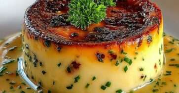 Flan de crabe démoulé, texture lisse et fondante, nappé d’une sauce crémeuse à la ciboulette, servi chaud dans une assiette élégante.