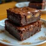 Carrés de brownies sans sucre au chocolat noir intense avec cœur au caramel fondant visible à la découpe, surface légèrement craquelée et texture dense et moelleuse, présentés sur une planche en bois.