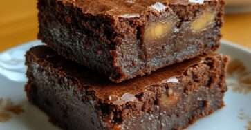 Carrés de brownies sans sucre au chocolat noir intense avec cœur au caramel fondant visible à la découpe, surface légèrement craquelée et texture dense et moelleuse, présentés sur une planche en bois.