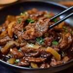 Bœuf sauté à l’oignon en fines lamelles, sauce soja brillante, oignons fondants et garniture d’oignons verts dans un wok