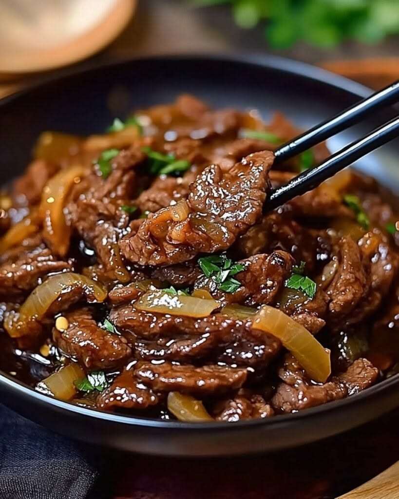 Bœuf sauté à l’oignon en fines lamelles, sauce soja brillante, oignons fondants et garniture d’oignons verts dans un wok