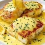 Pavés de cabillaud au four nappés de sauce crémeuse à la moutarde et au citron, garnis de persil frais dans un plat en céramique