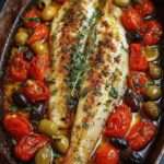 Filets de poisson méditerranéen blanc au four avec tomates cerises rôties, olives vertes et noires, rondelles de citron et herbes fraîches dans un plat méditerranéen