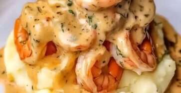 Crevettes à l'ail dorées nappées d’une sauce crémeuse à l’ail et aux herbes, servies sur une purée de pommes de terre lisse et onctueuse