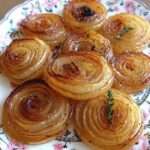 Rondelles épaisses d’oignons rôtis au miel et au thym, dorées et légèrement caramélisées sur une plaque de cuisson