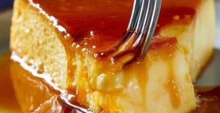 Flan vénézuélien ultra crémeux démoulé sur un plat, nappé de caramel ambré coulant, surface lisse et brillante, part découpée montrant une texture fondante.