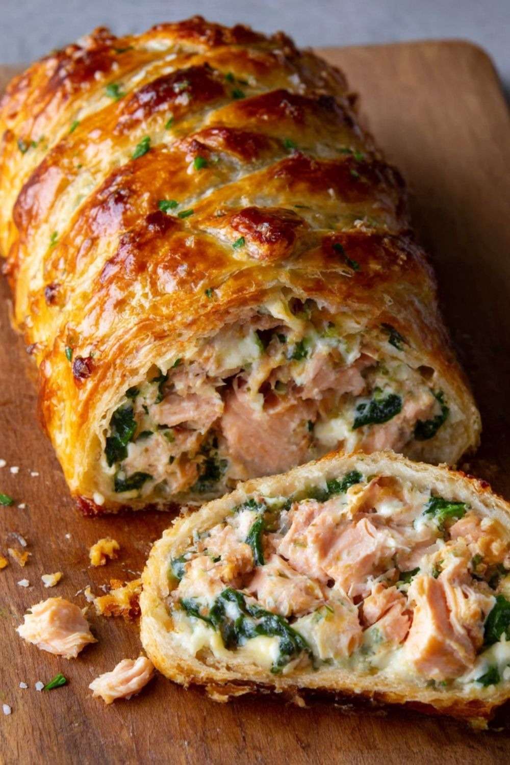 Saumon en croûte aux épinards coupé en tranches, pâte feuilletée dorée et croustillante, cœur de saumon rosé et garniture crémeuse aux épinards.