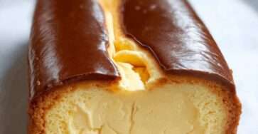 Cheesecake basque crémeux cuit dans un moule à cake, avec surface dorée caramélisée et intérieur fondant, servi en tranches sur une assiette.