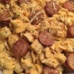 Assiette de pâtes crémeuses au poulet et saucisse fumée, nappées d’une sauce au fromage, garnies de persil frais et de parmesan râpé.