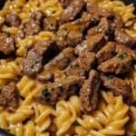 Assiette de pâtes crémeuses au steak, beurre et ail, nappées d’une sauce au parmesan avec morceaux de bœuf tendres et persil frais.